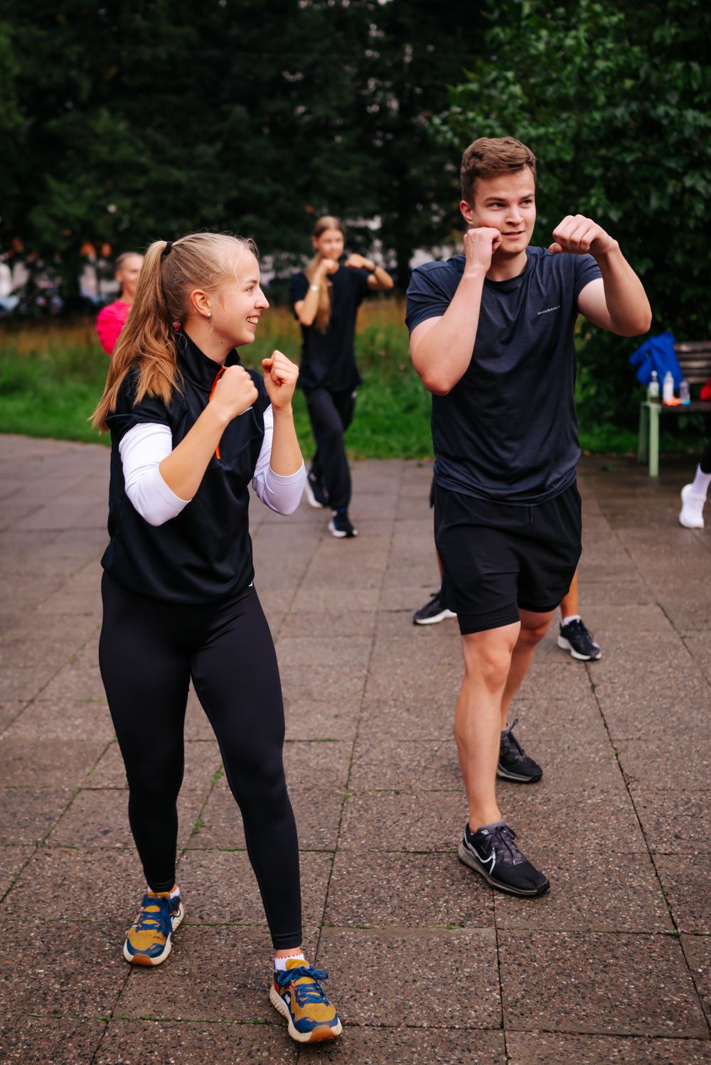 Two participants practicing boxing stance and form during an outdoor fitness class.