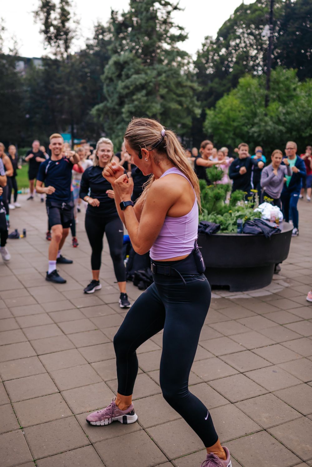 Group fitness participant performing boxing moves during an outdoor exercise class.