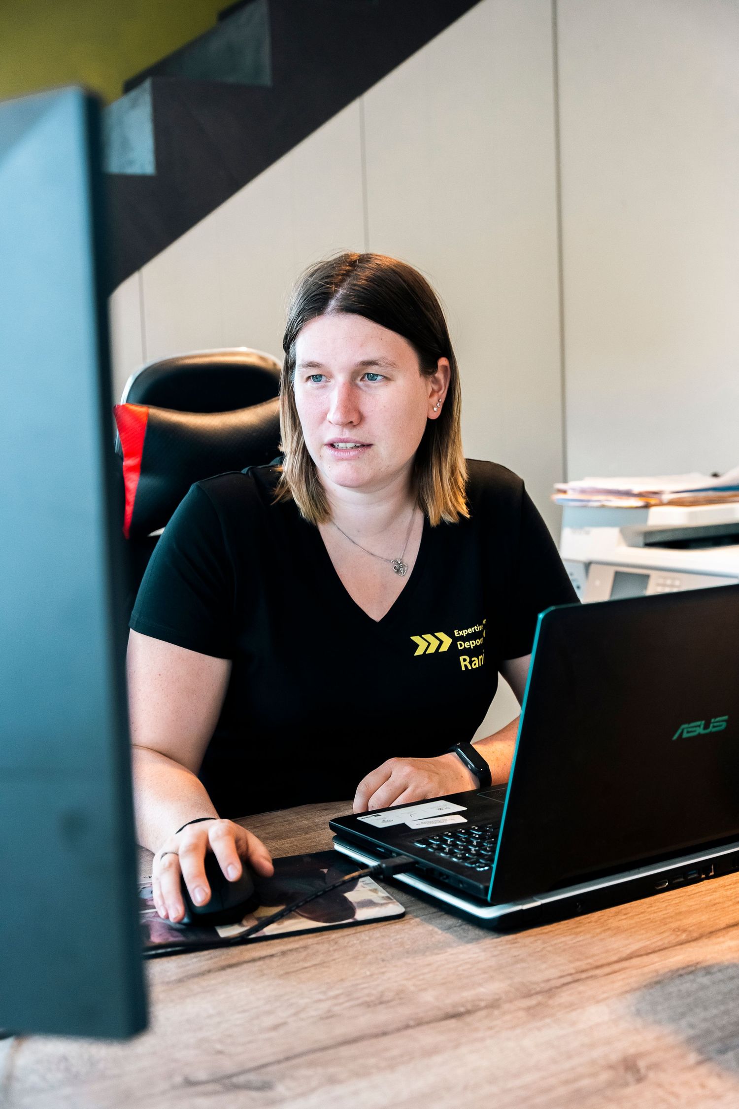 Professional working on laptop at desk while wearing company branded uniform.