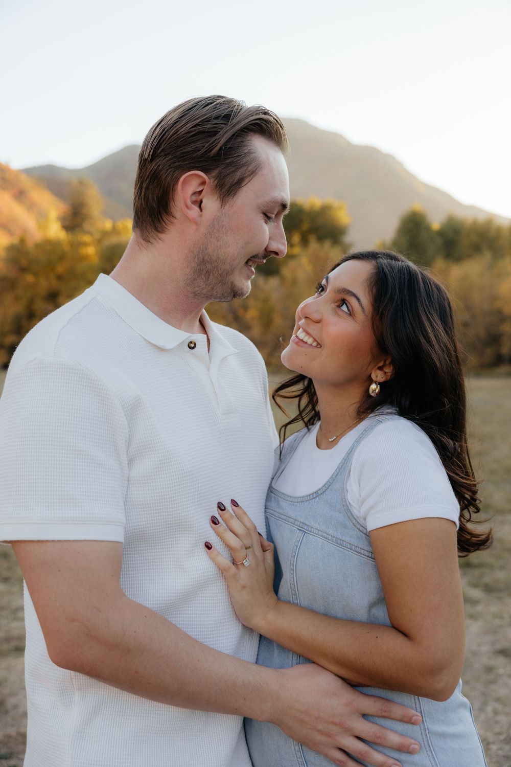 Couple gazing at each other lovingly in a warm golden autumn mountain meadow.