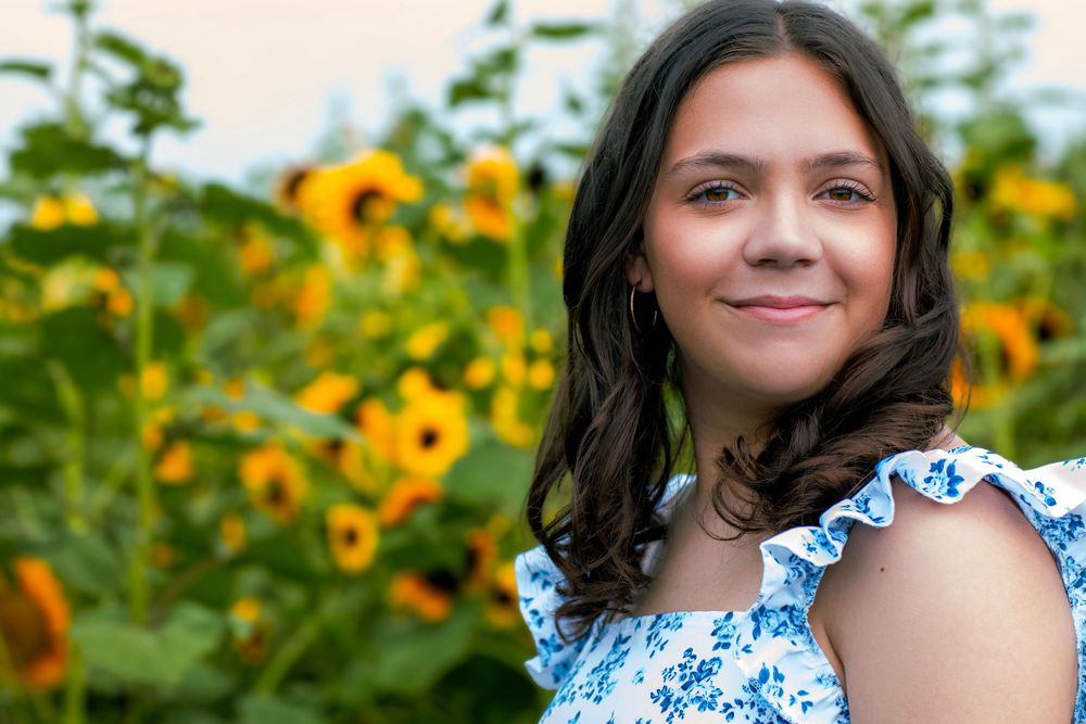 Summer portrait amidst blooming sunflowers in floral dress.