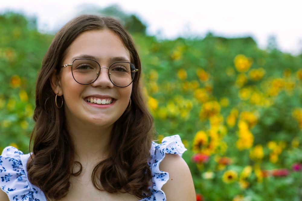 A cheerful garden portrait with sunflowers and yellow flowers in the background.