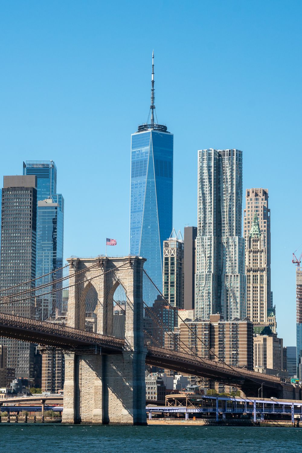 One World Trade Center and Brooklyn Bridge with Manhattan skyline viewed from the East River.