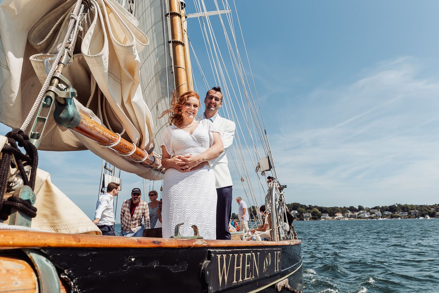 Couple embracing on sailboat deck during sunny day on water.