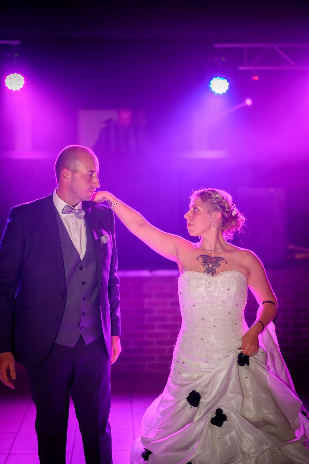 A couple dances romantically under dramatic purple lighting at their wedding reception.