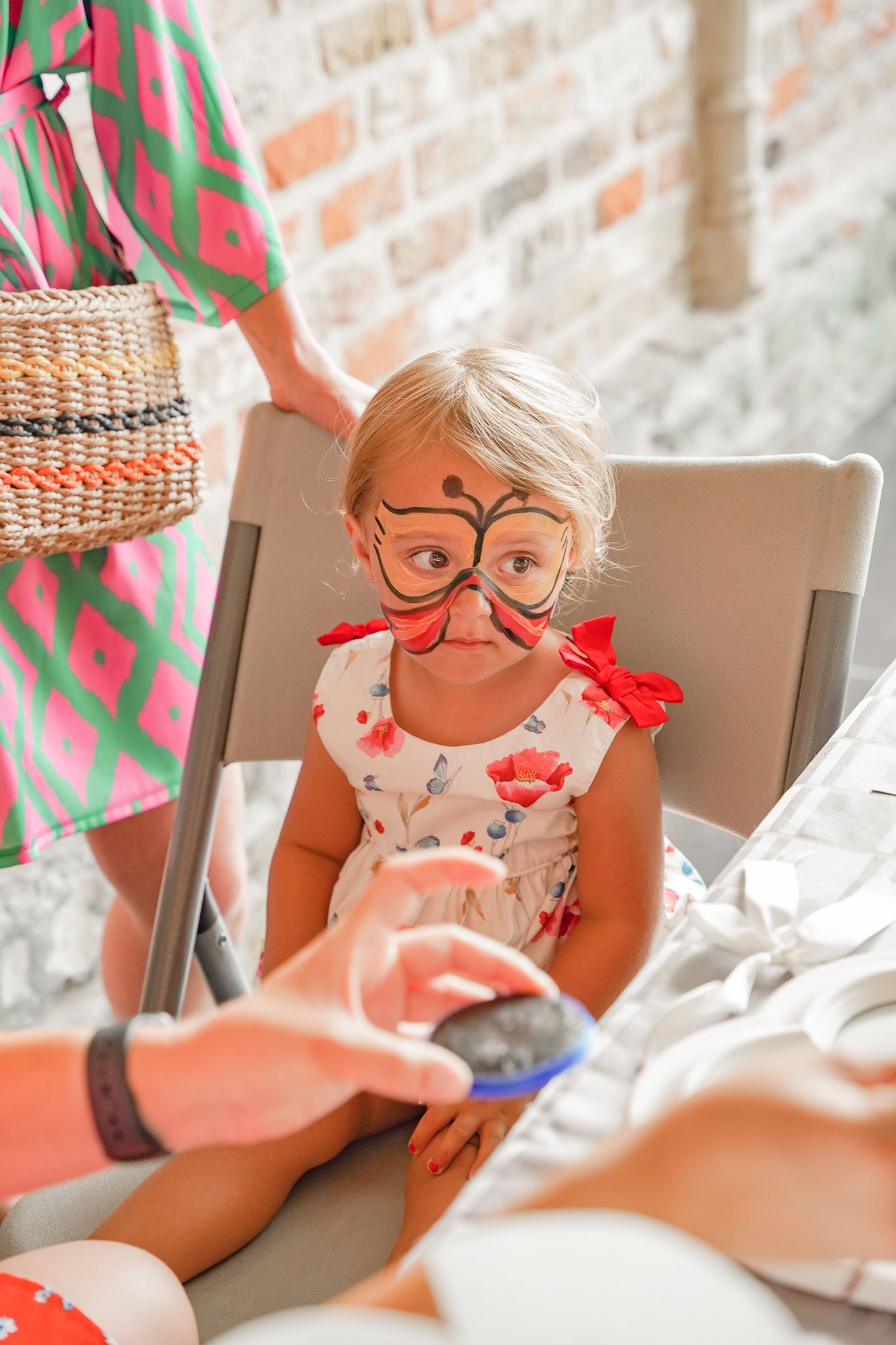 Child wearing funny glasses and red bows sitting in chair.