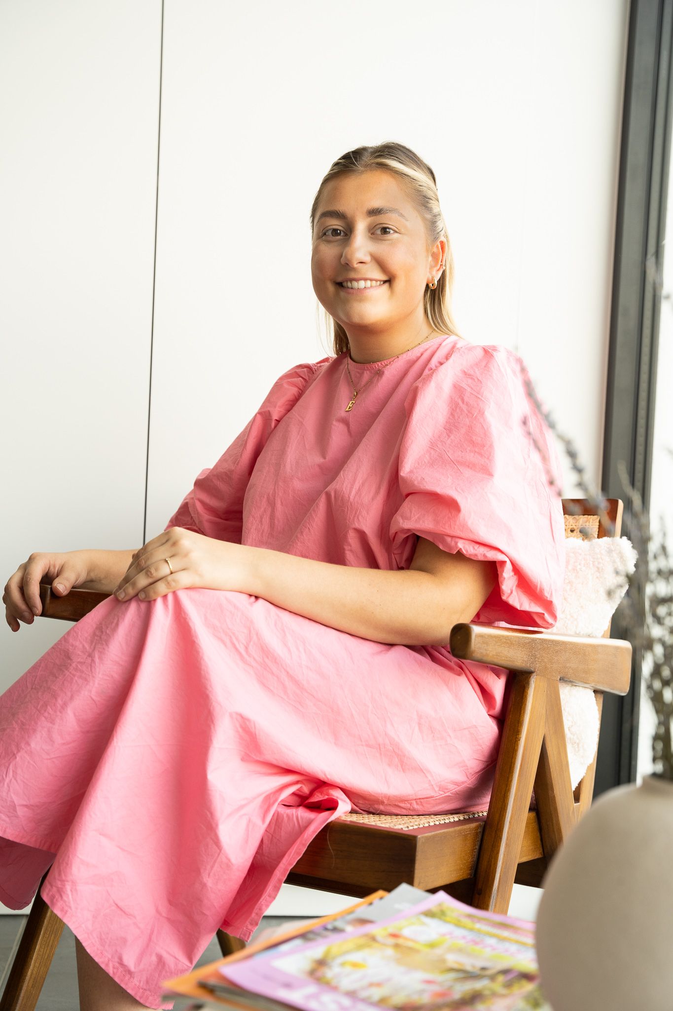 Casual portrait in bright interior space with wooden chair.