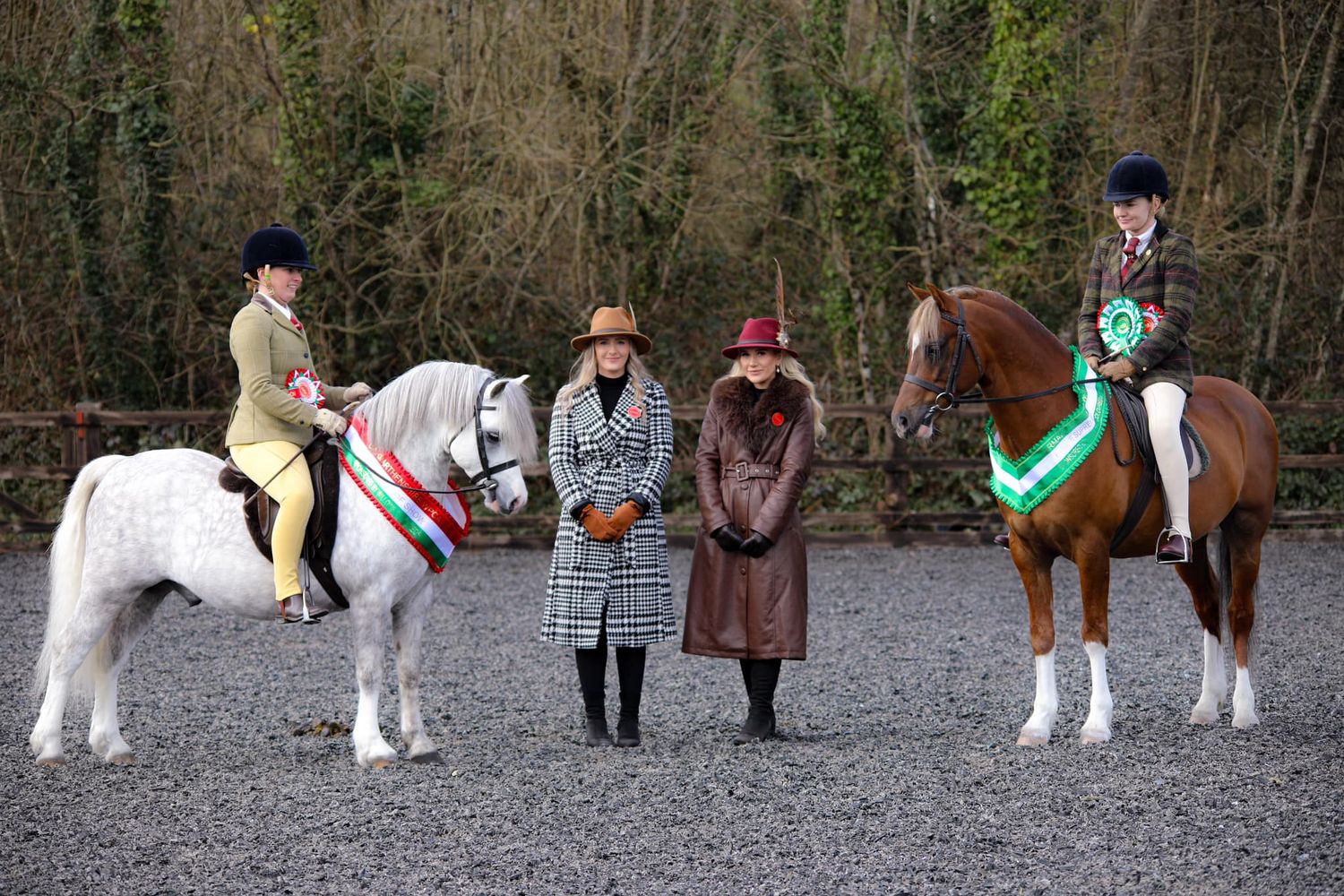 Group of equestrians with two mounted horses and handlers in riding attire.