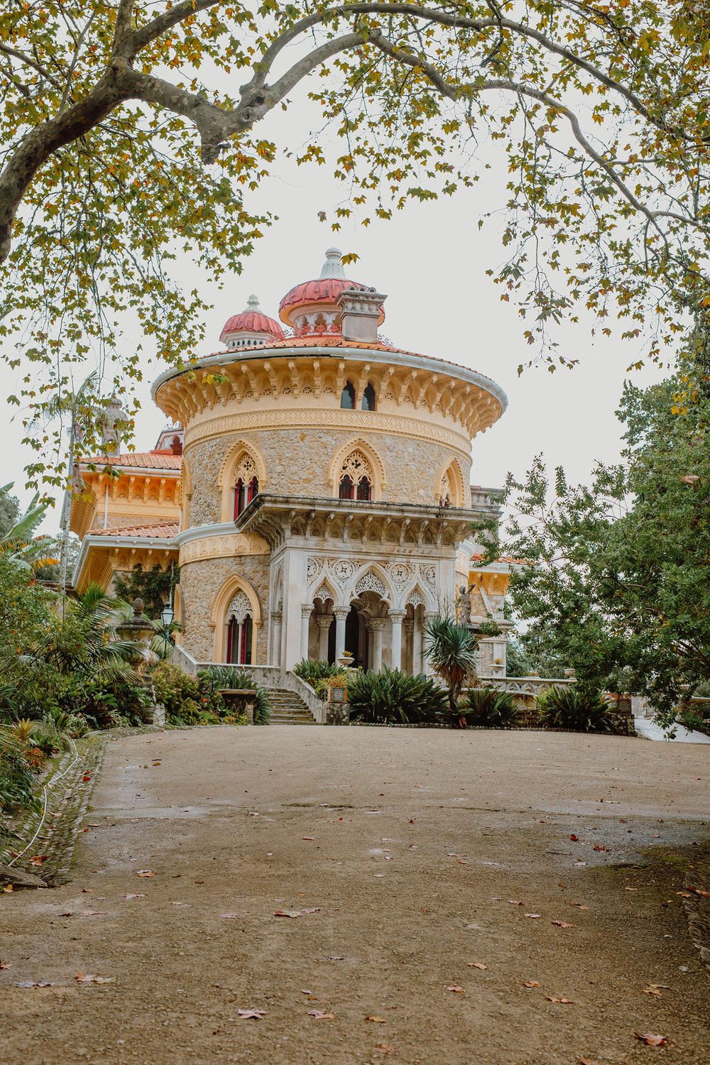 A panoramic view of an ornate palace with domed architecture and decorative columns surrounded by autumn trees.