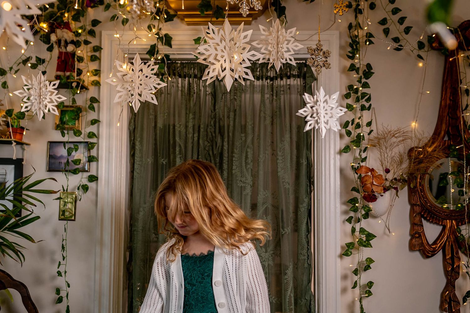 Holiday decorated room with hanging snowflakes, ivy garlands, and velvet curtains creating a magical atmosphere.