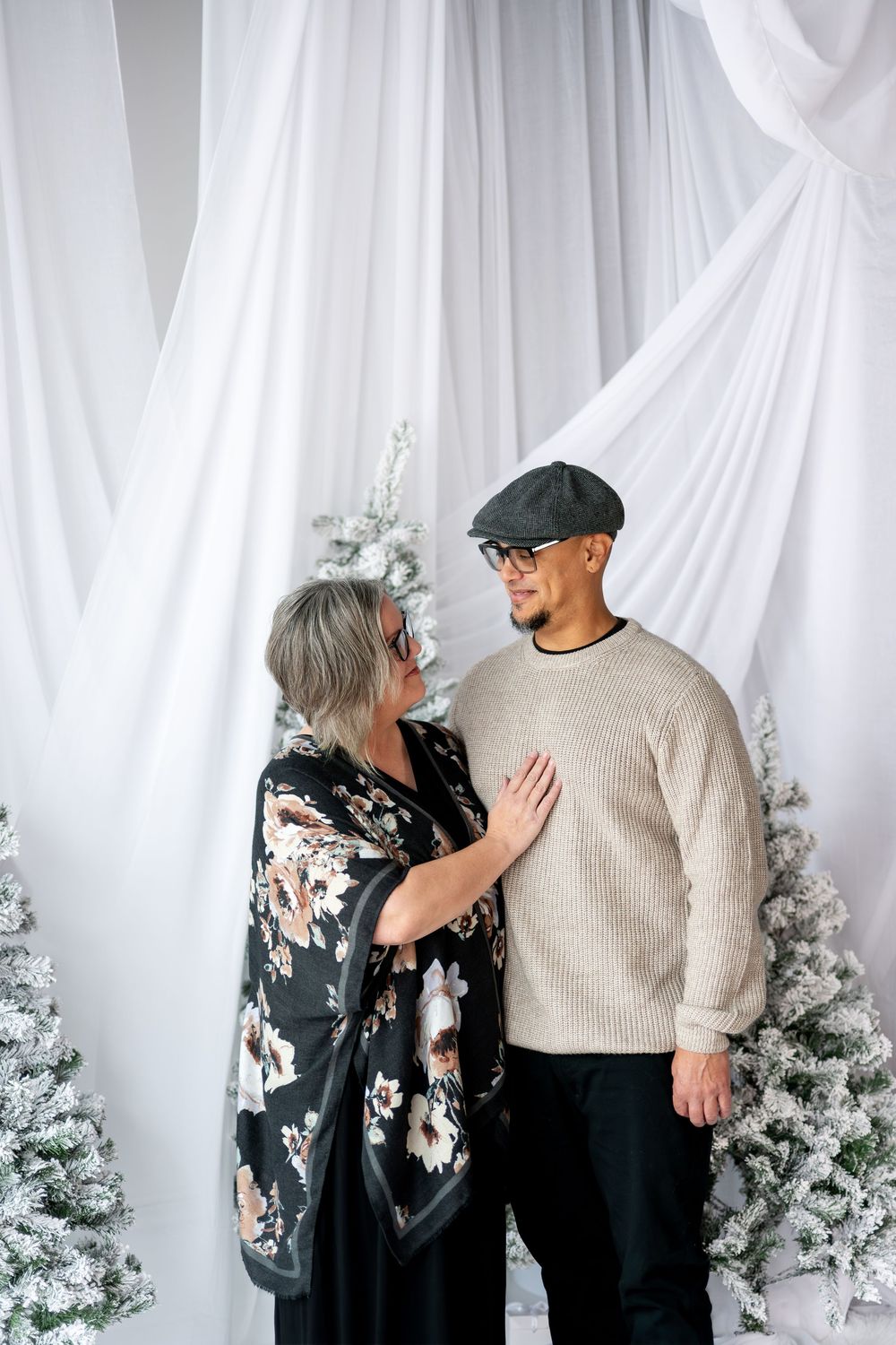 Woman placing hand on mans chest as they share an intimate moment by Christmas trees.
