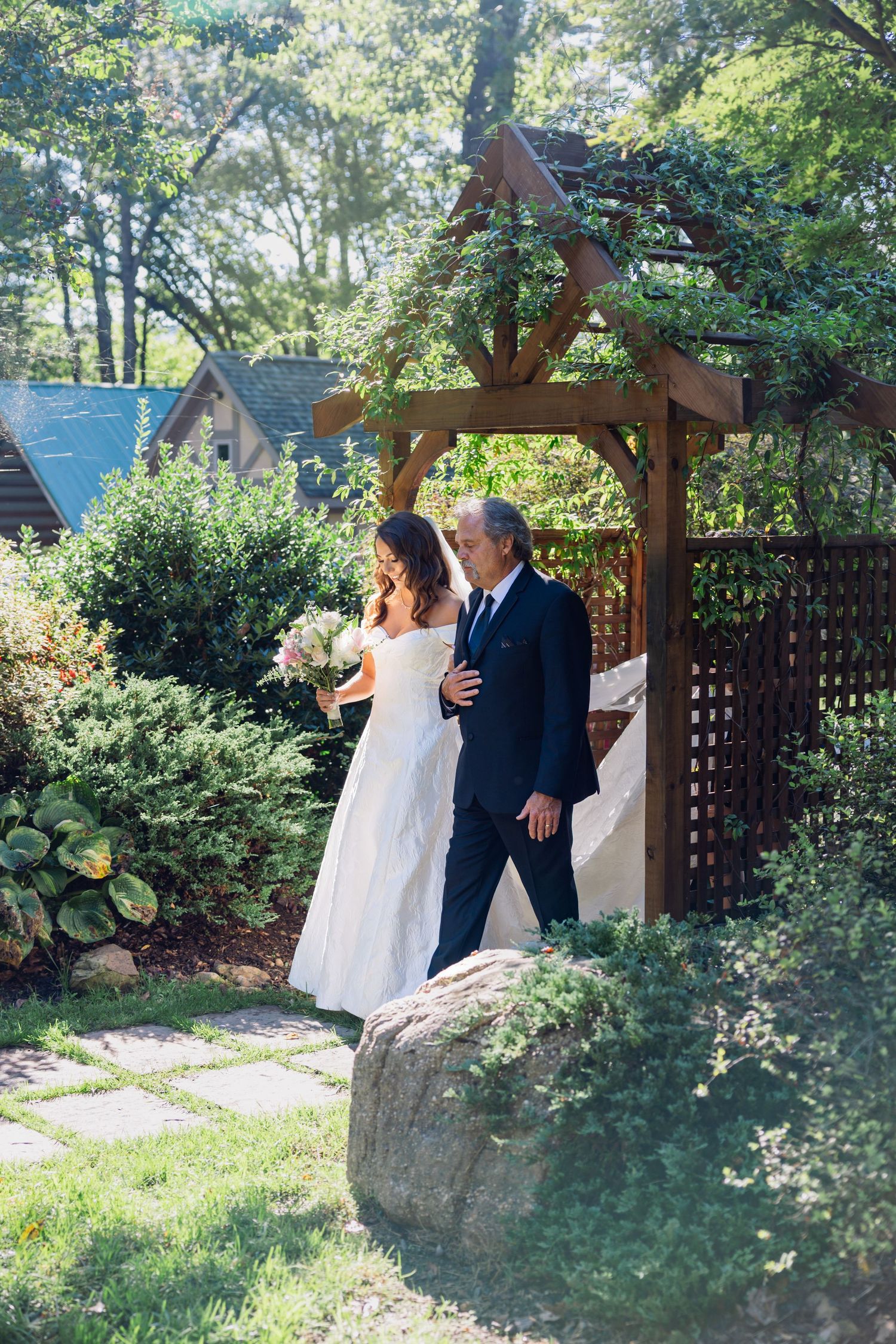 White satin bow decorations adorn a wooden surface alongside delicate floral arrangements in peach and pink tones.