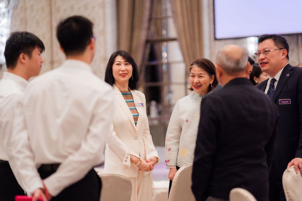 A group of people in formal attire interact and socialize at what appears to be a business or networking event.