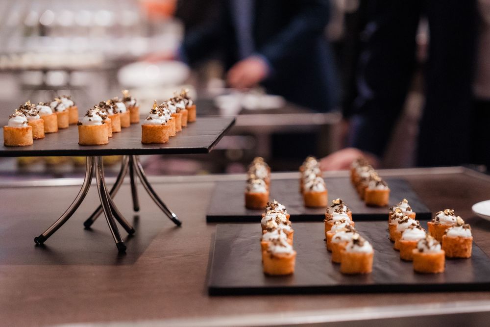 Mini pumpkin cupcakes with cream cheese frosting arranged on dark wooden serving boards in a restaurant setting.