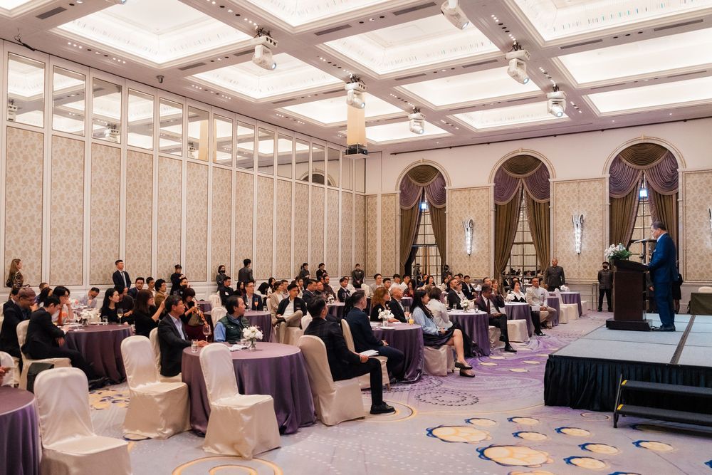 Elegant ballroom setup with white chair covers and round tables arranged for a formal event under crystal chandeliers.