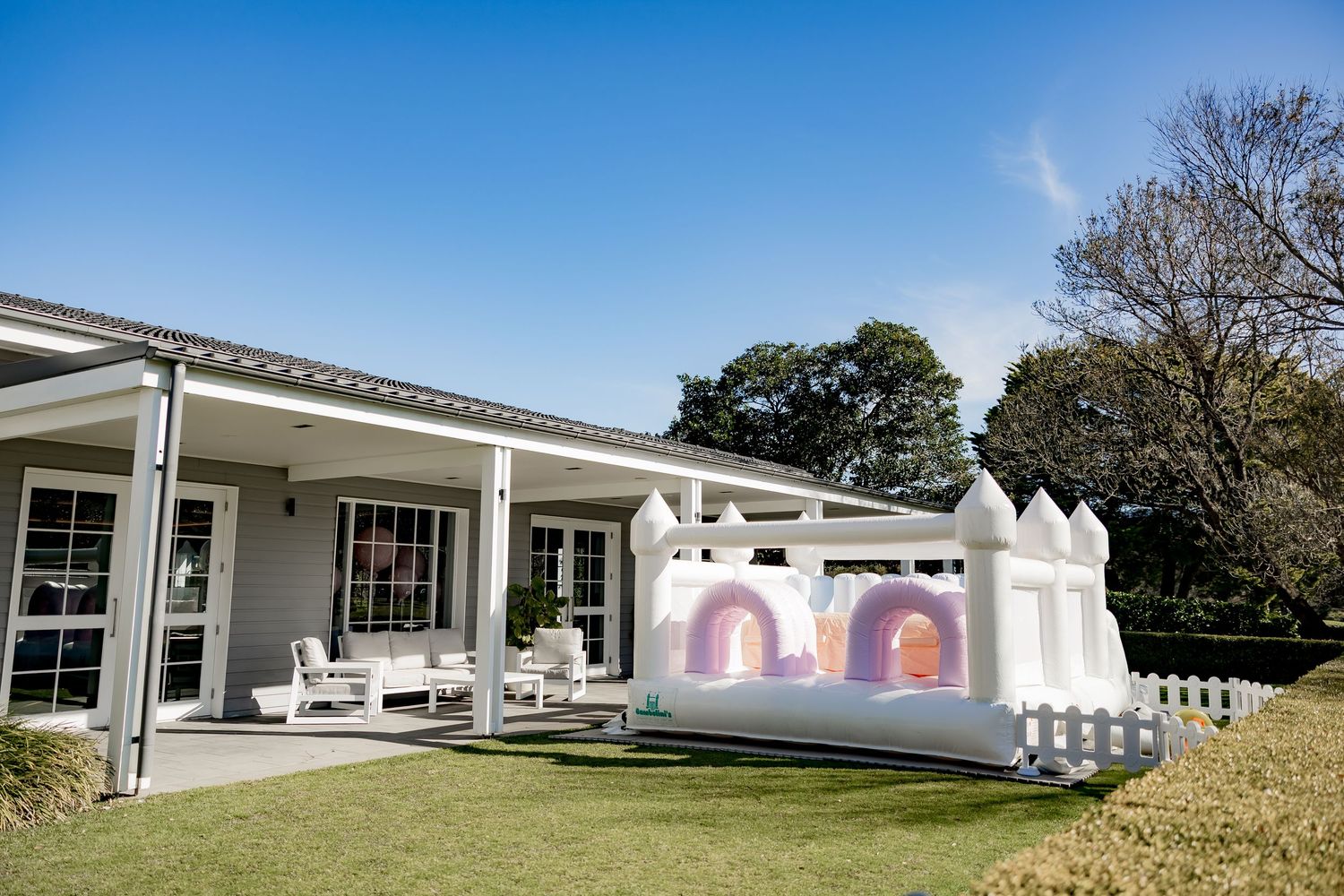 A panoramic view of a white modern residential building exterior with multiple connected sections and landscaping.