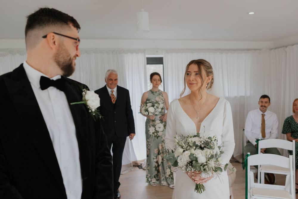 Bride and groom share a joyful moment at the altar as wedding guests look on during ceremony.