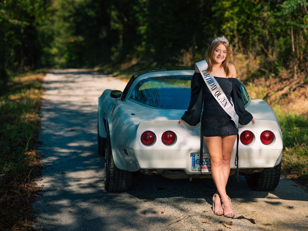 Young girl at birthday photo session with tiara, banner, and car