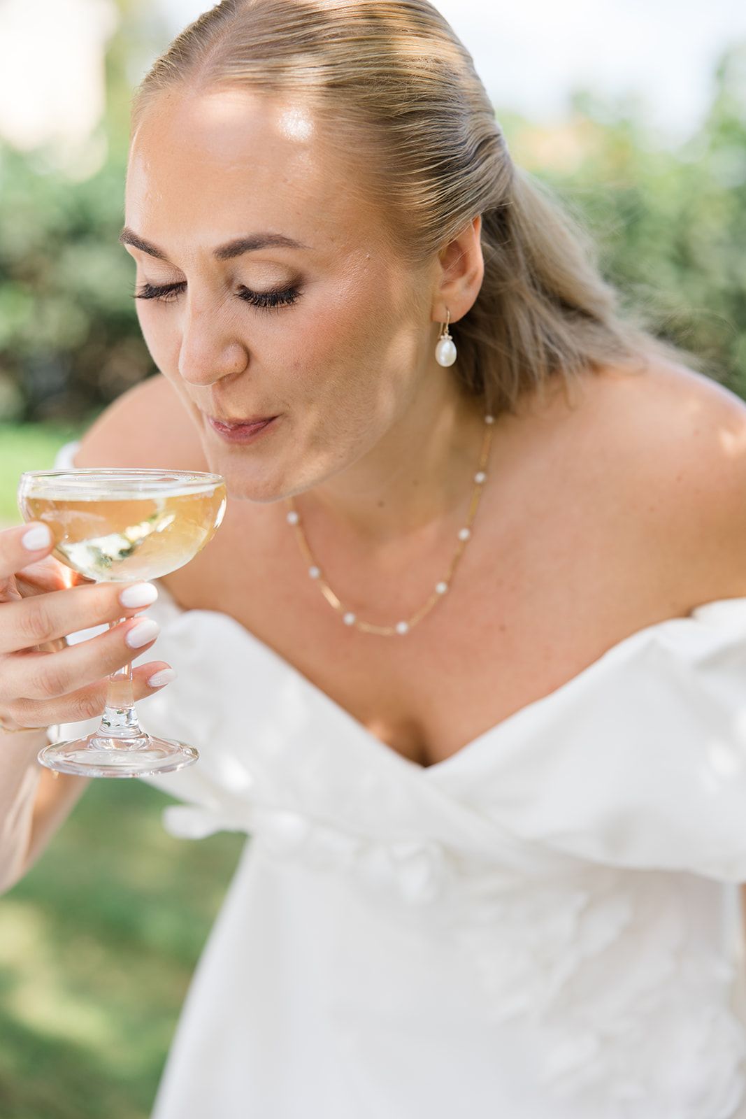 A bride in a white dress sips champagne from a glass in a sequence of elegant outdoor photos.