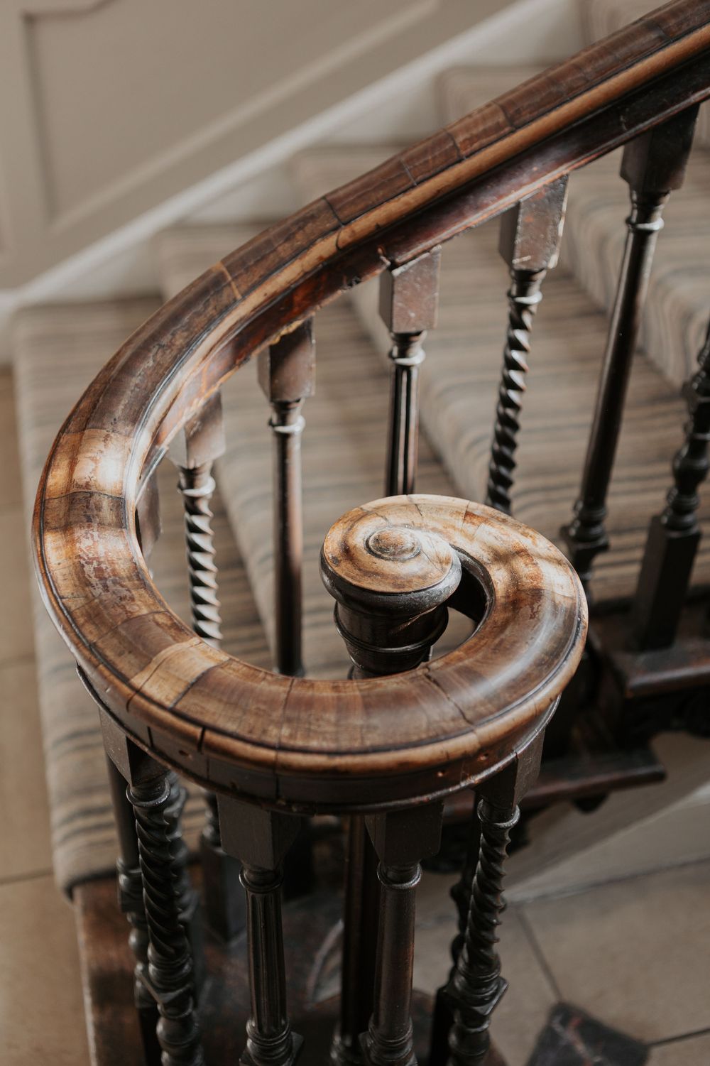 Polished dark wood spiral staircase banister with twisted spindles detail.