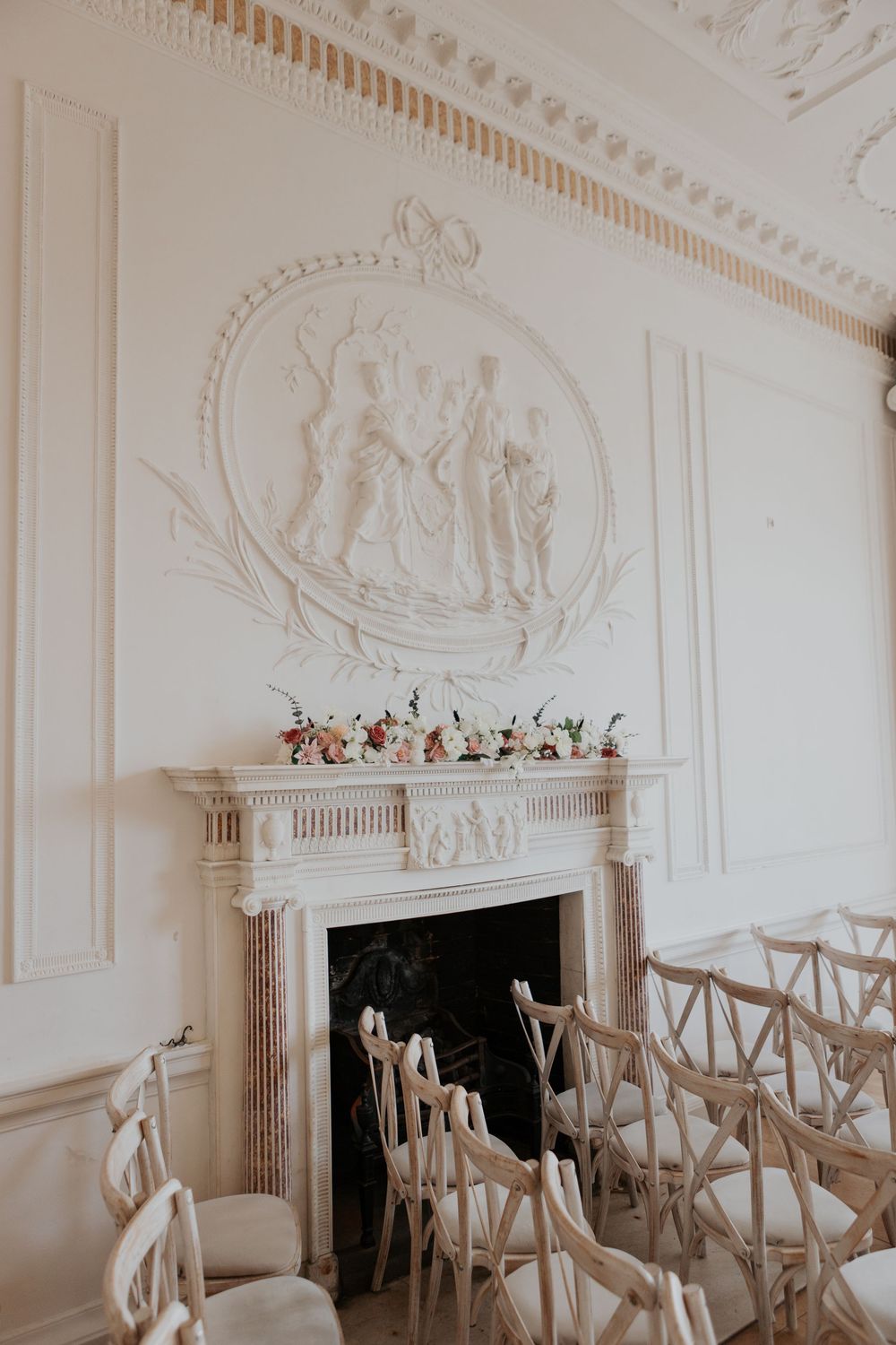White wedding ceremony room with neoclassical plasterwork relief above fireplace.