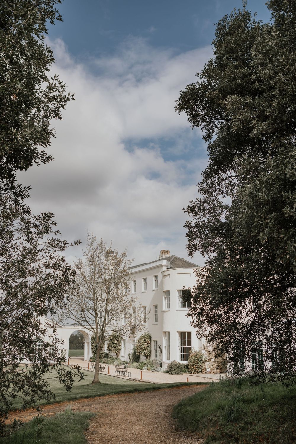 Grand white Georgian manor house wedding venue framed by lush mature trees.