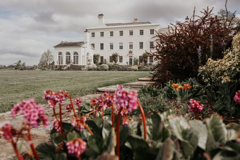 Elegant white Georgian country house wedding venue surrounded by colorful spring gardens.