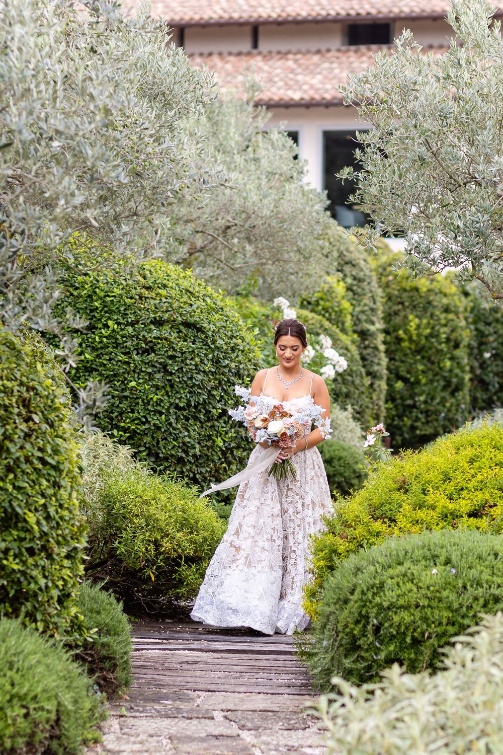 Bride walking through olive trees during a luxury destination wedding in Italy.