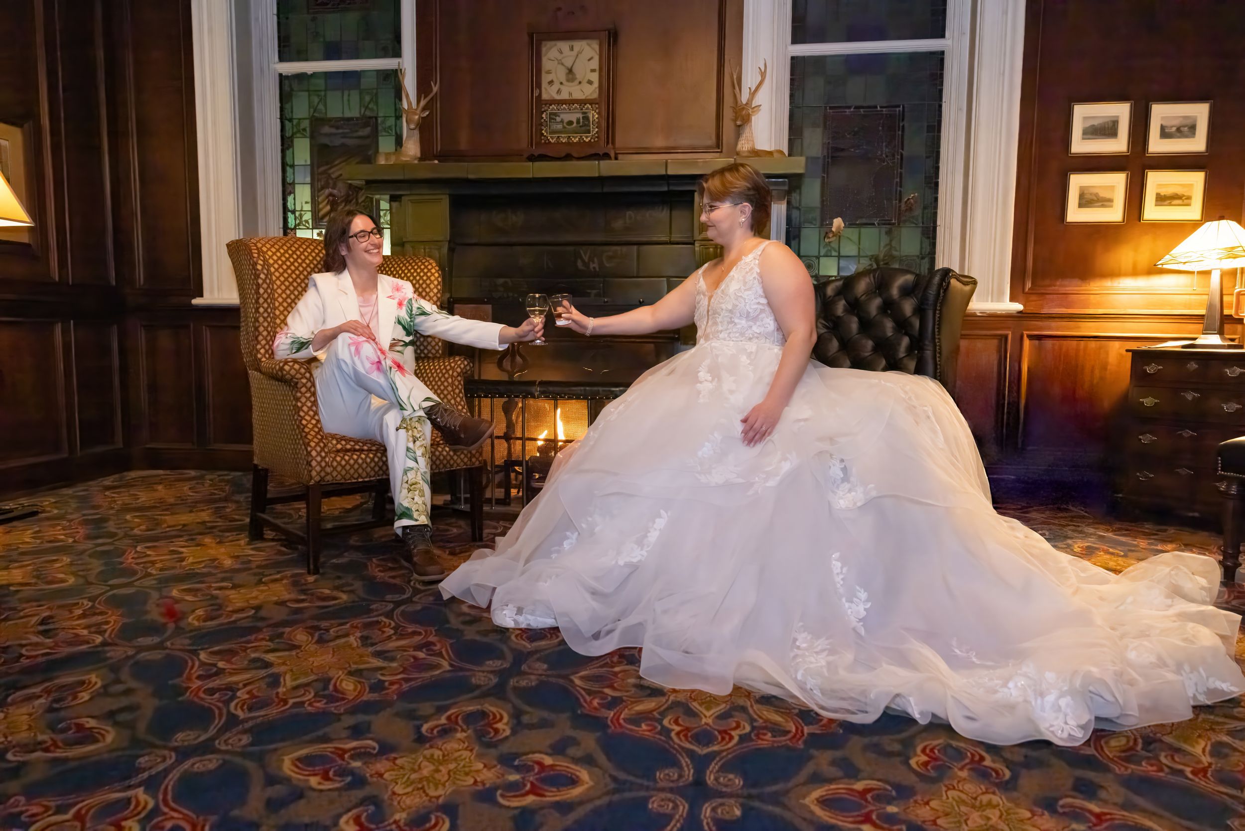 A bride in a white wedding gown sits elegantly on a vintage couch in an ornate room with antique furnishings.
