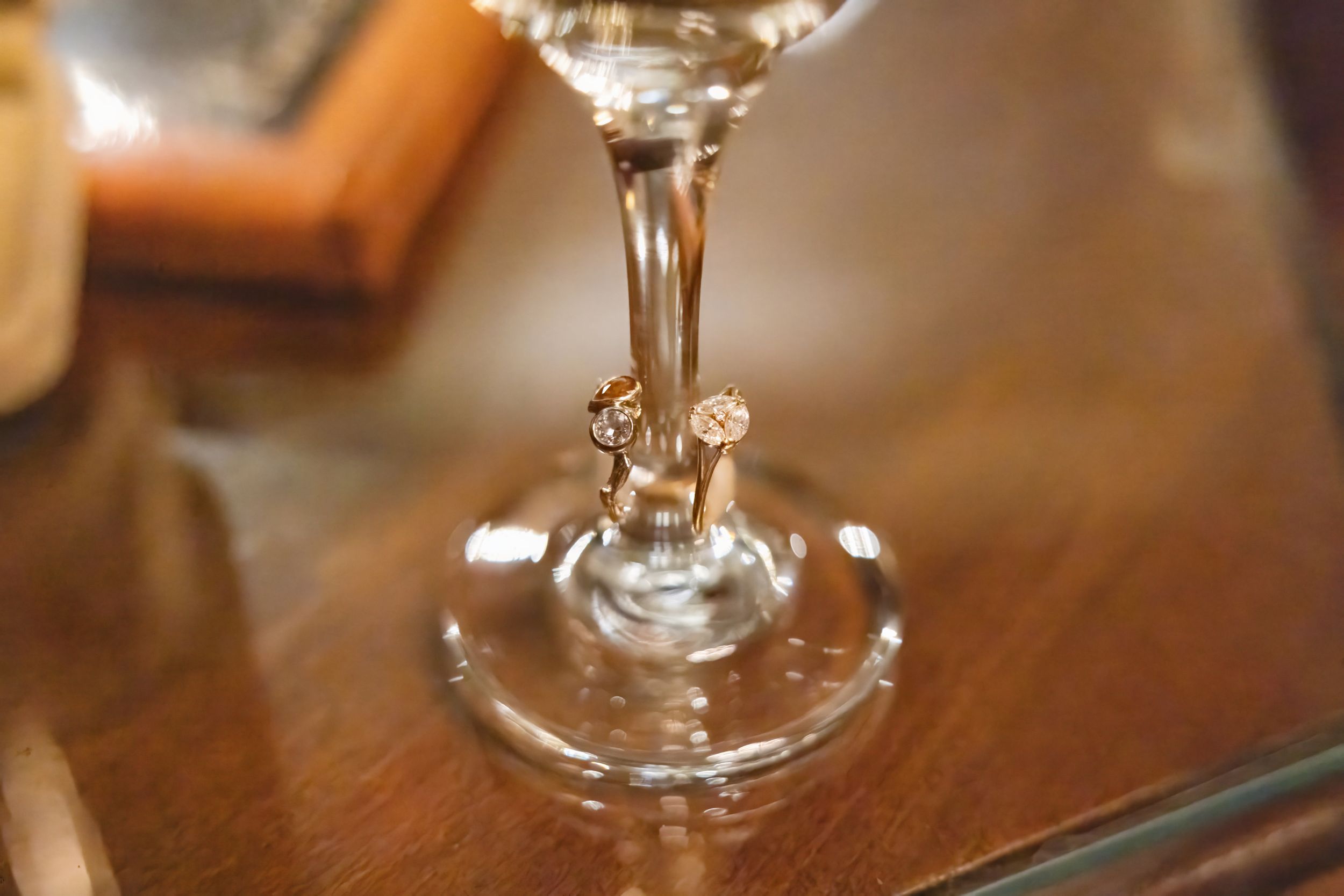 Close-up view of an elegant wine glass stem on a polished wooden surface.