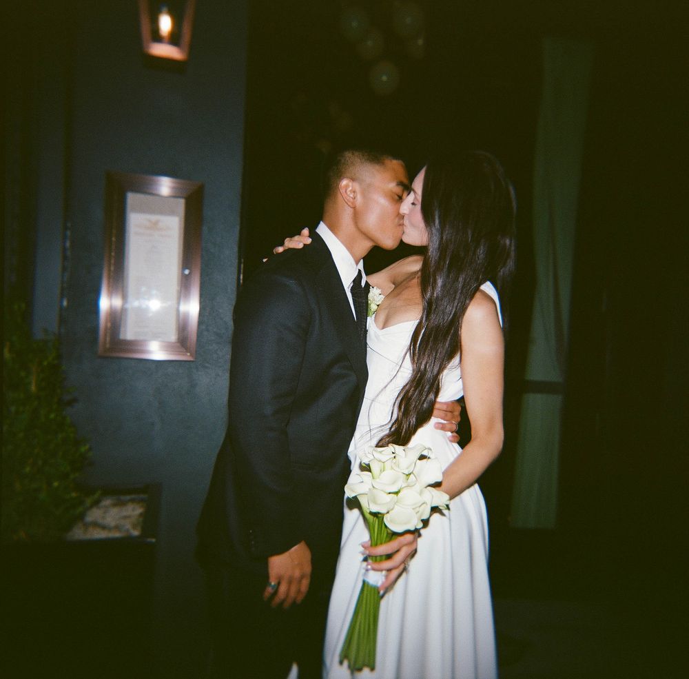A romantic wedding couple embraces in a dimly lit venue during their first dance.