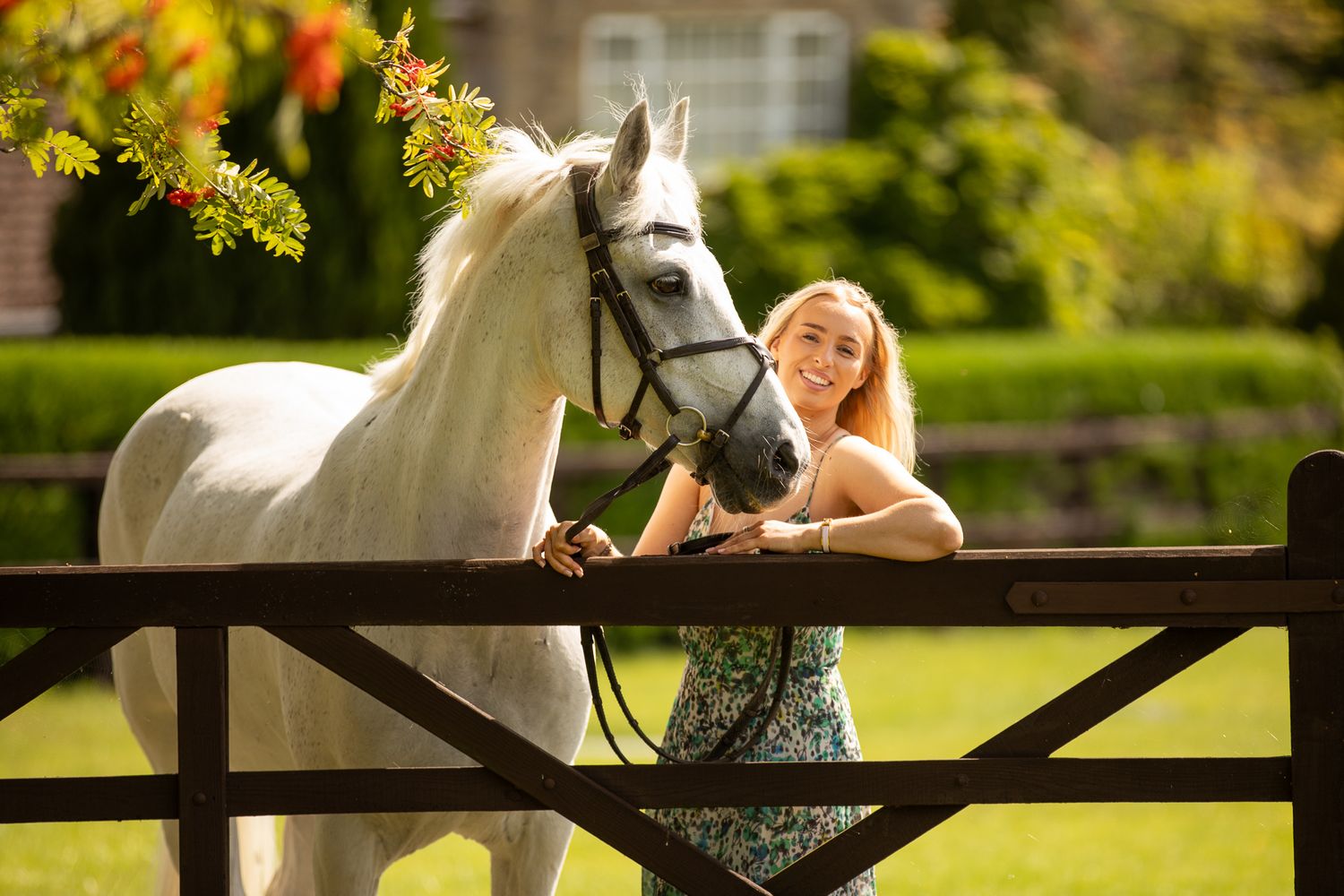Two joyful riders lean over a white horse's back in a sun-drenched field at golden hour.