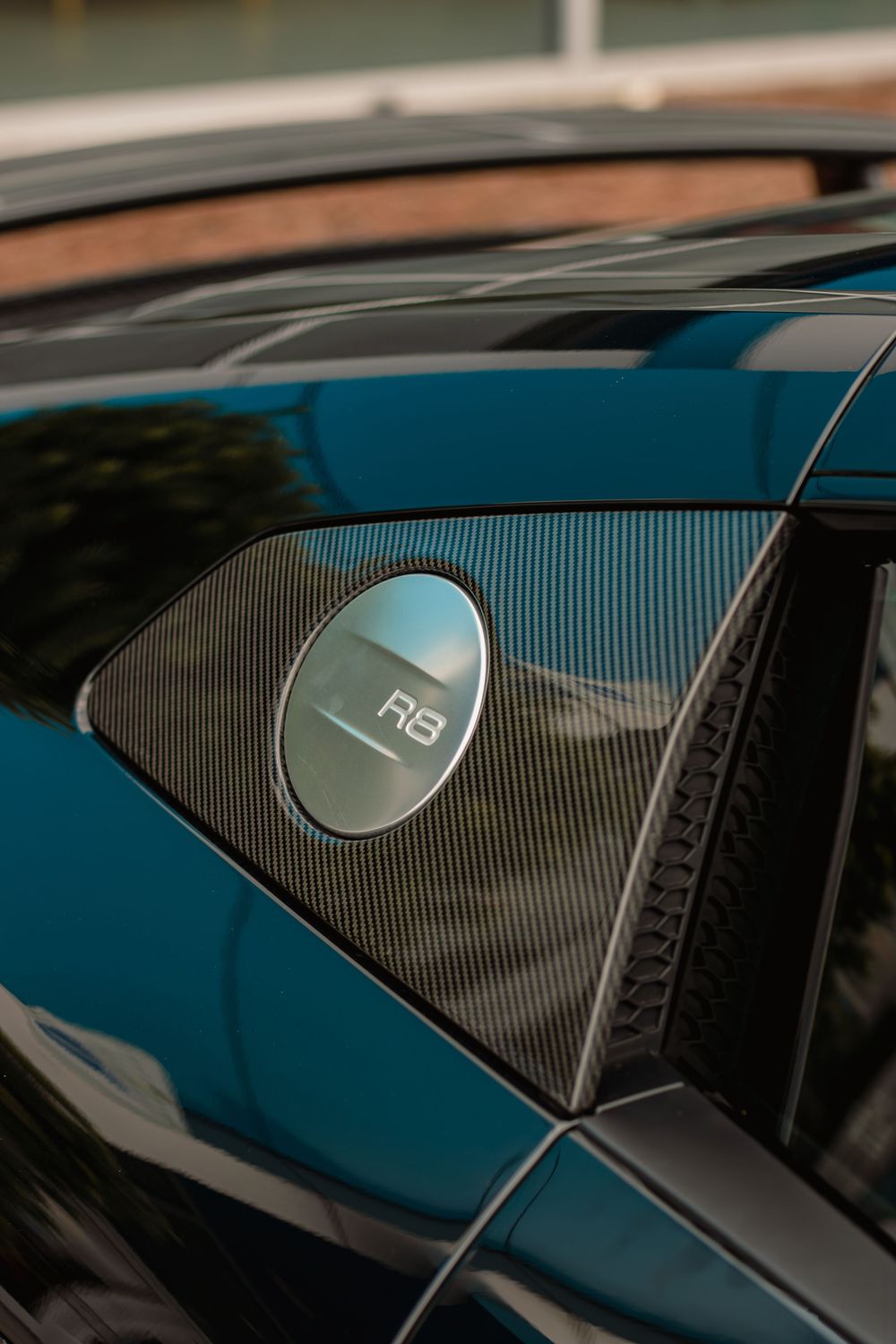 Close-up view of a car's exterior showing multiple chrome B&O speaker badges on dark tinted windows.