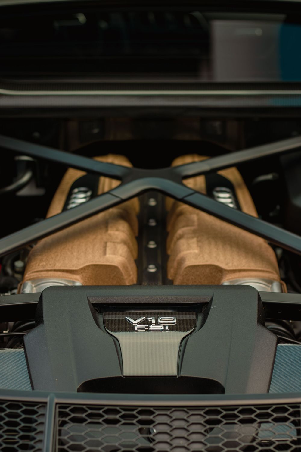 Close-up view of a black honeycomb grille pattern and hood design on a modern performance vehicle.