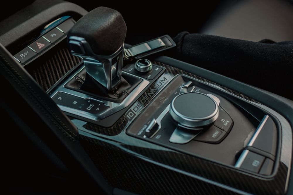 Interior view of luxury car dashboard showing black leather trim and modern control interface details.