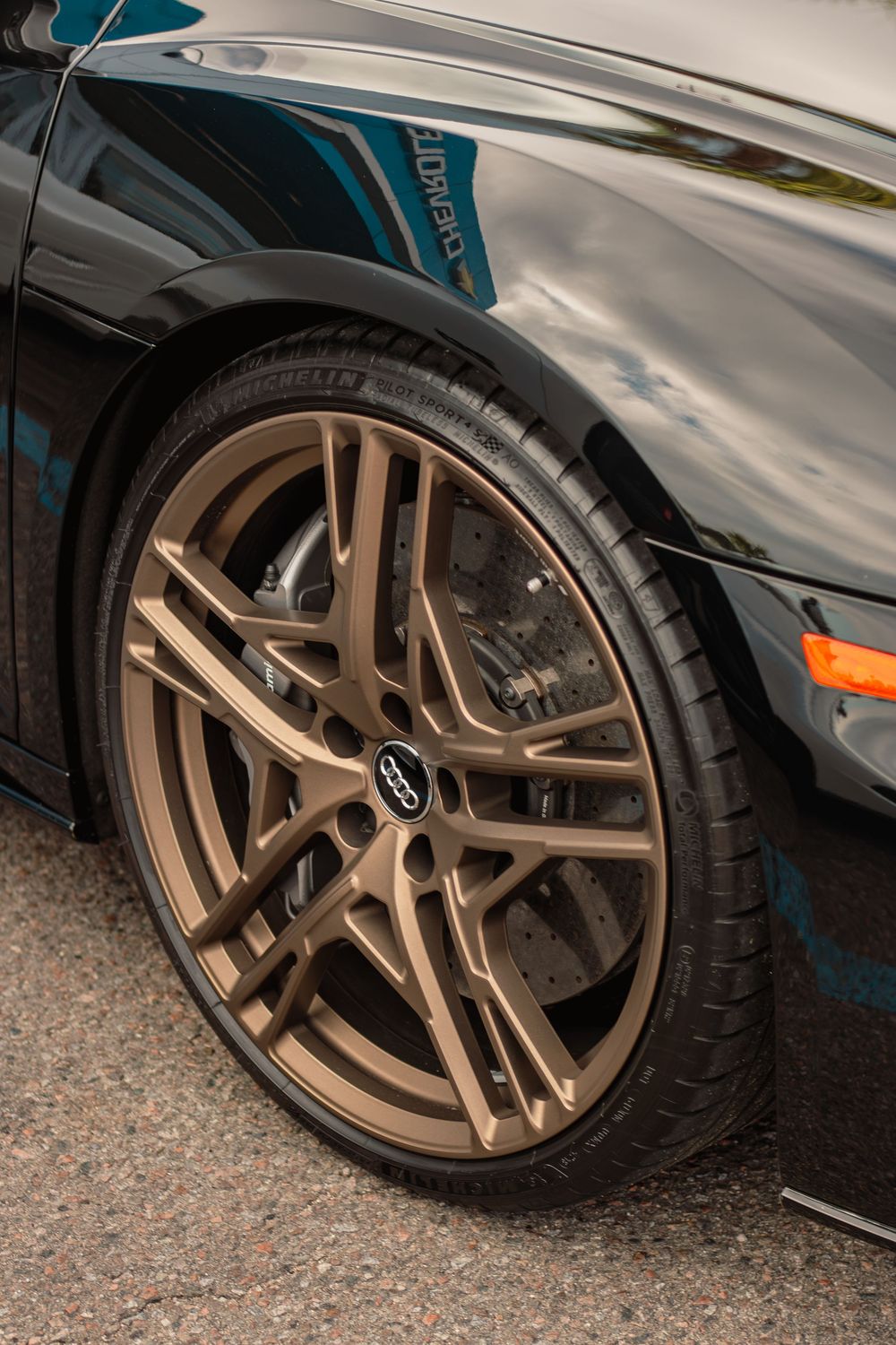 Close-up sequence of bronze alloy wheels on a black car showing different angles and tire fitment details.