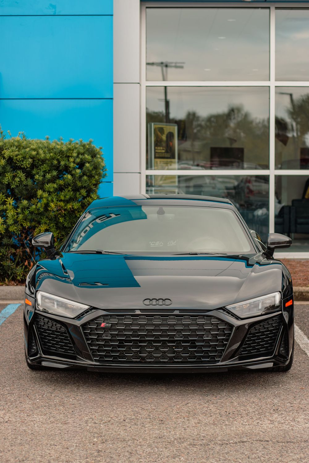 Sleek black Audi R8 supercar shown in a progressive sequence of front-end detail shots against a blue building exterior.