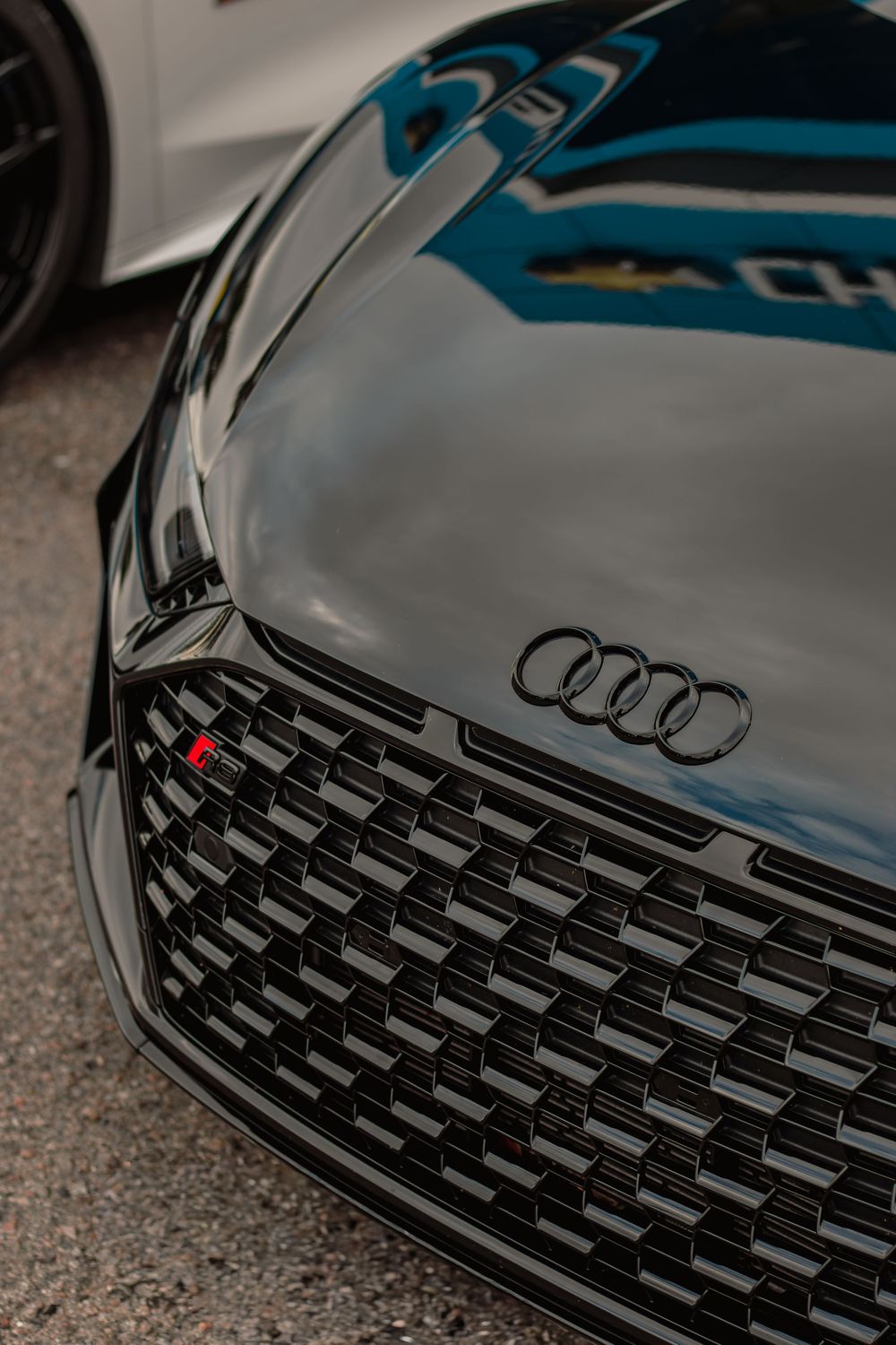 Close-up view of a modern Audi vehicle's glossy black front grille with chrome logo detail.