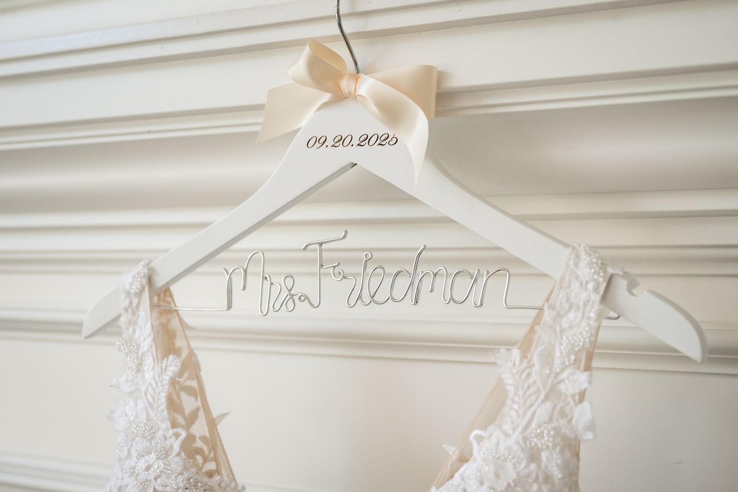 White wooden wedding dress hanger with personalized name and date detail.