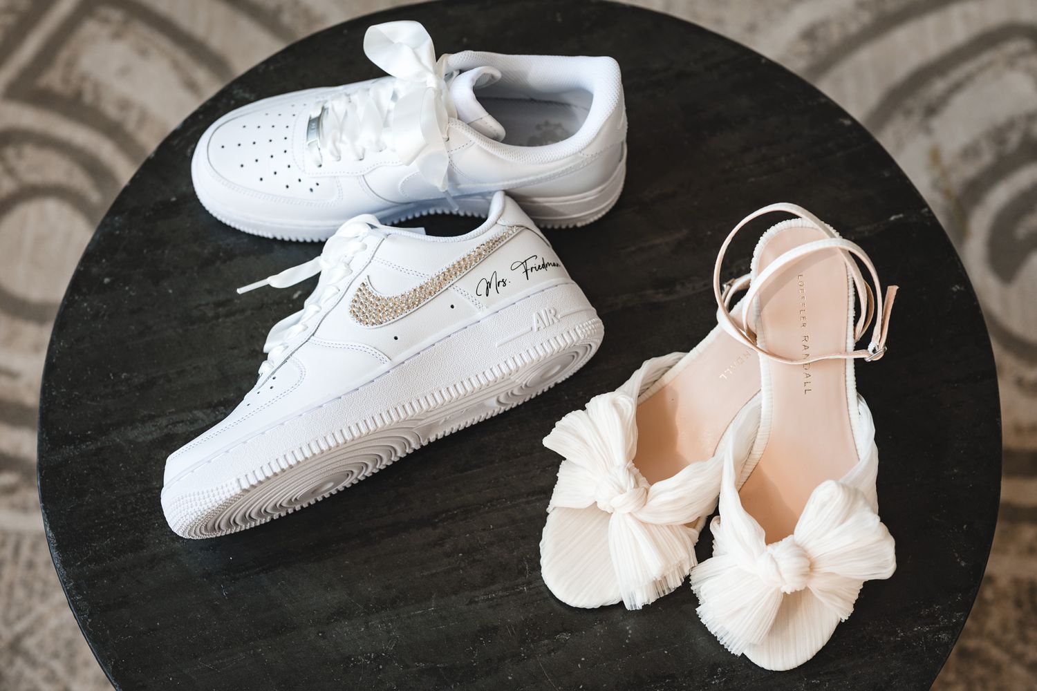 White Nike Air Force 1 sneakers next to bridal heels on dark surface.