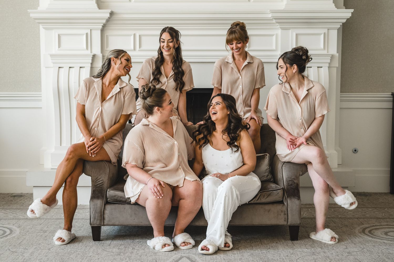 Group relaxing on couch in matching getting ready outfits during wedding preparations.