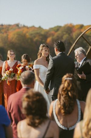 Wedding guests mingling during an outdoor autumn reception with fall foliage in background.