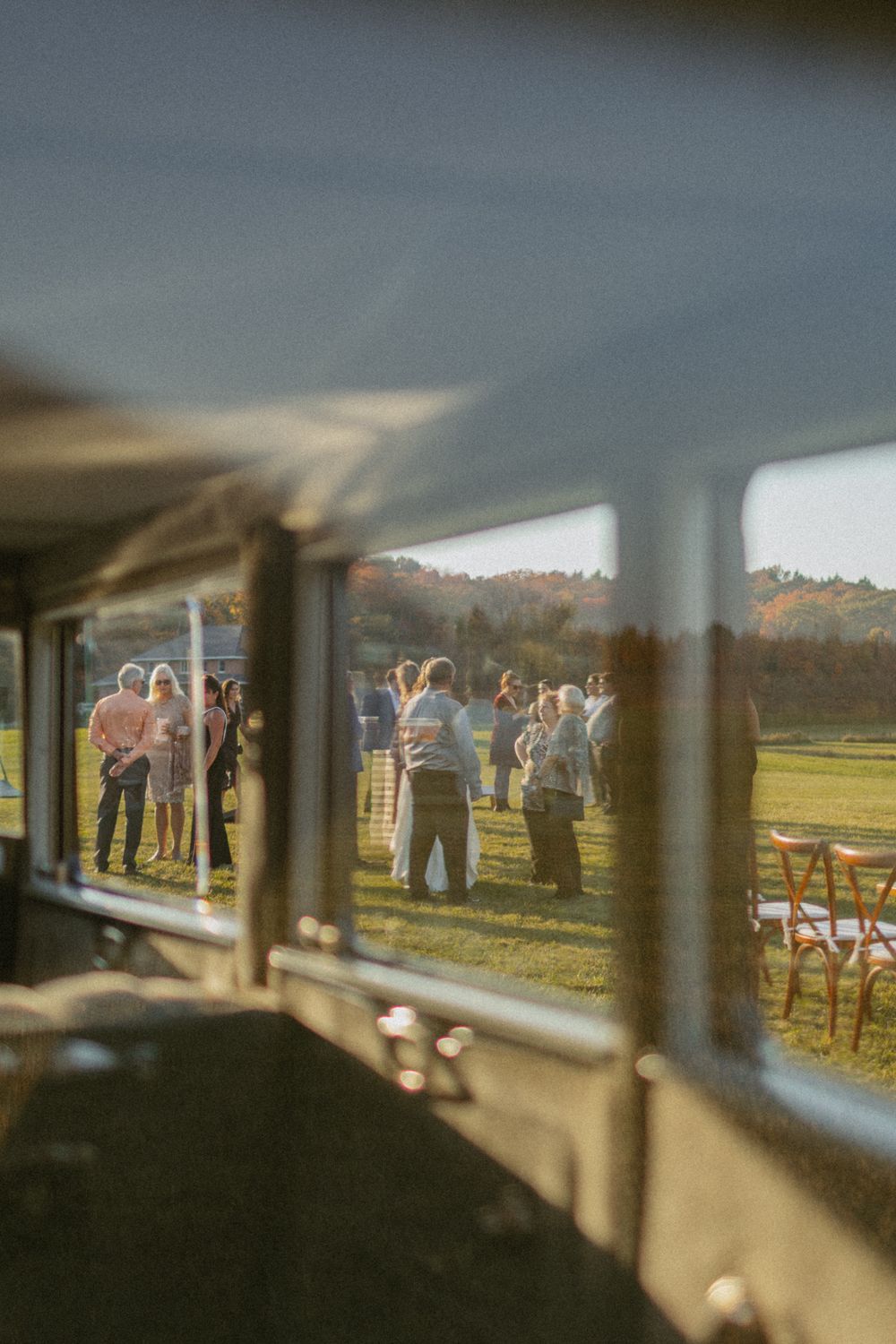 Wedding ceremony viewed through architectural elements with guests in distance.