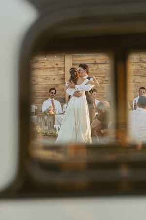 Wedding ceremony moment viewed through wooden fence slats in rustic setting.