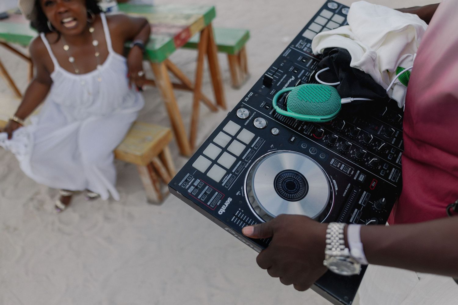 Close-up view of hands operating DJ equipment and turntables at an outdoor event.