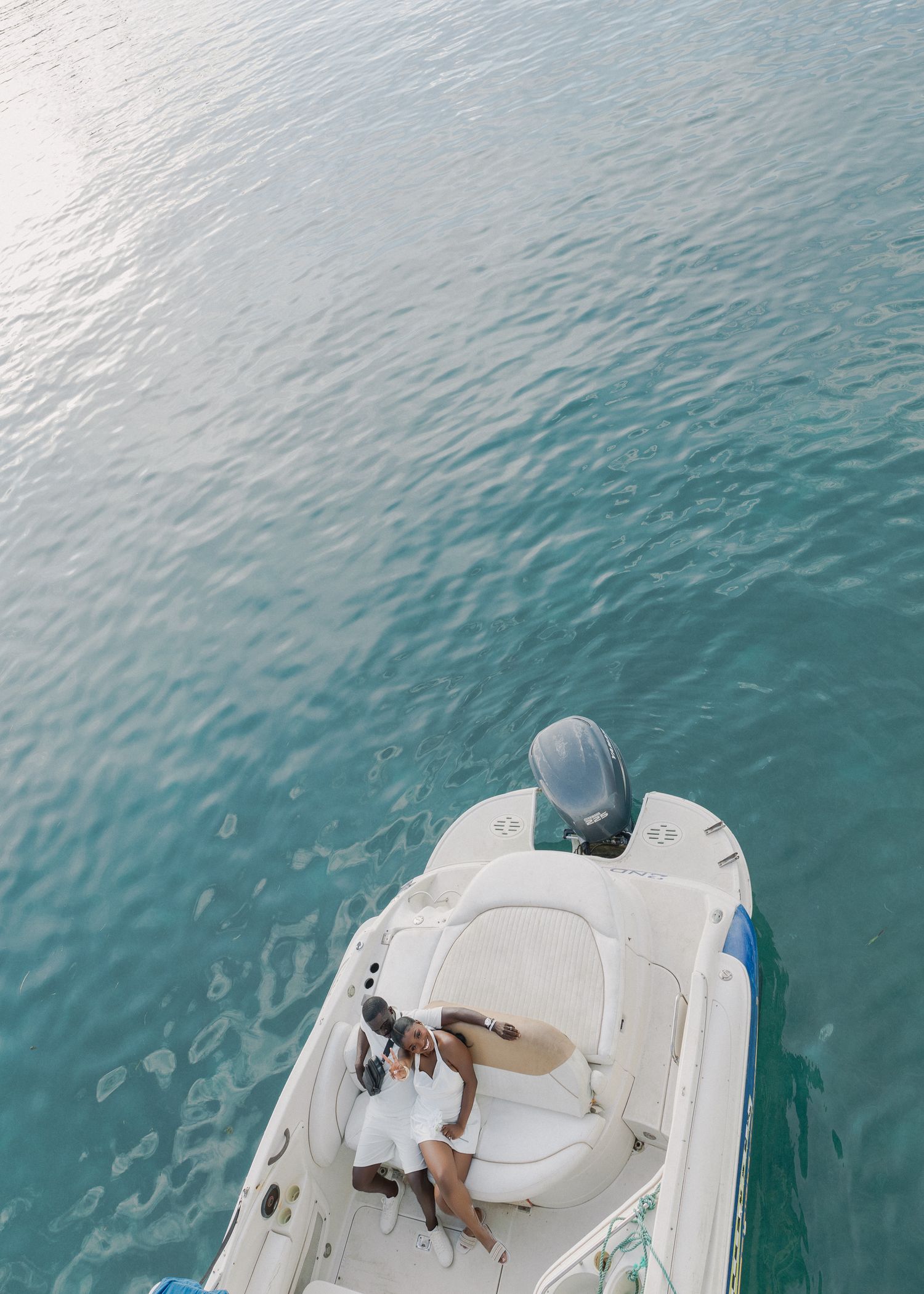 Aerial view of a white boat cruising through turquoise tropical waters on a sunny day.