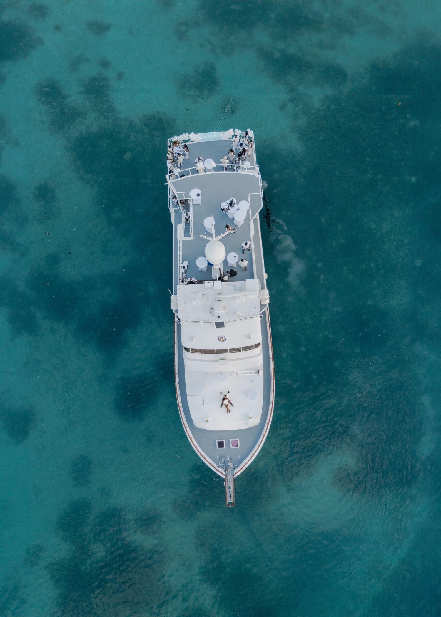 Aerial view of white boats anchored in crystal clear turquoise waters creating a stunning pattern from above.