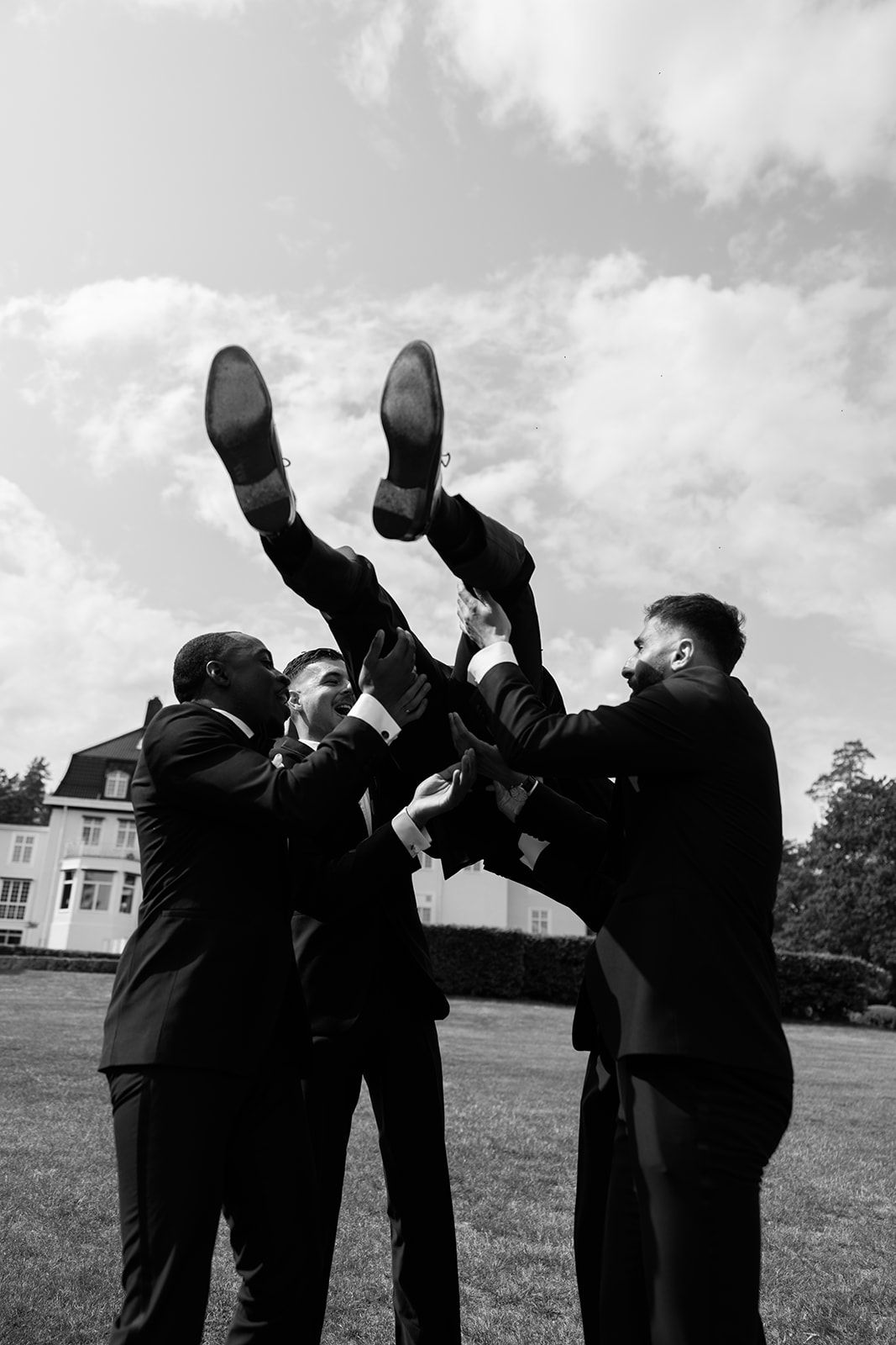 A sequence of five black and white photos showing groomsmen drinking from flasks in matching suits on a lawn.