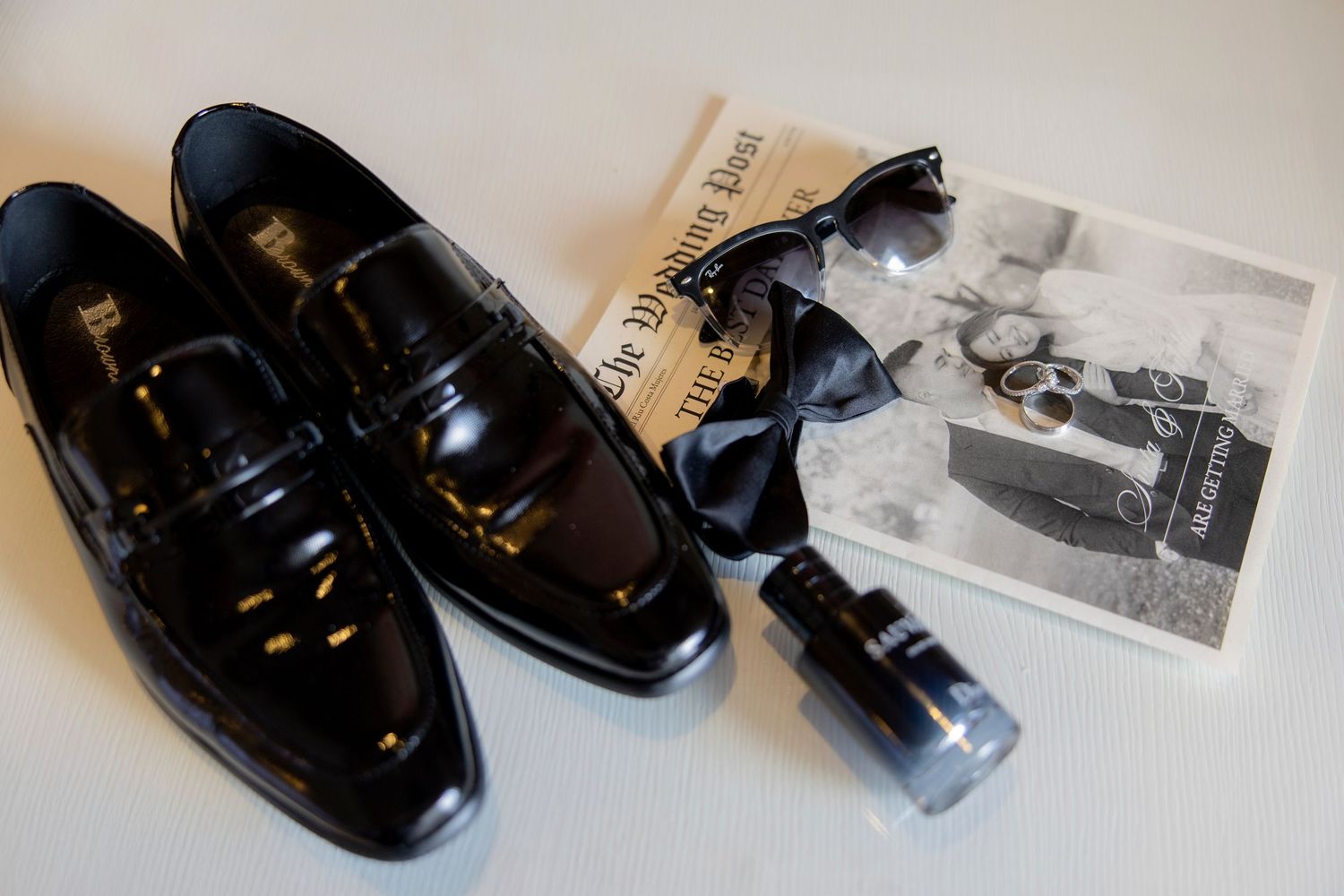 Black leather dress shoes displayed in various angles with packaging and product documentation on white surface.