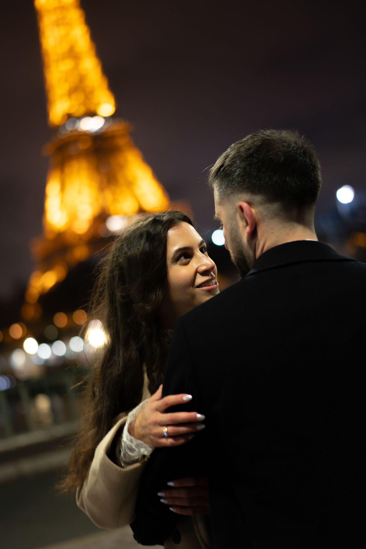 Romantic couple embracing at night in Paris with the illuminated Eiffel Tower glowing in the background. Best paris wedding photographer